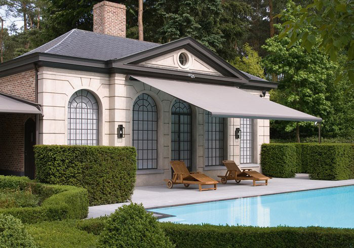 Die Terrassenmarkise Opal Design 2 in grau an nostalgischem Ferienhaus mit Pool und Garten.